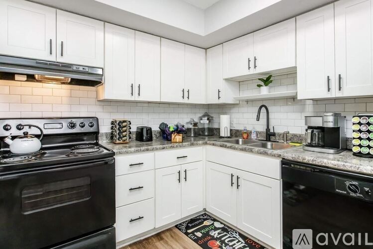 A kitchen with black appliances and white cabinets.