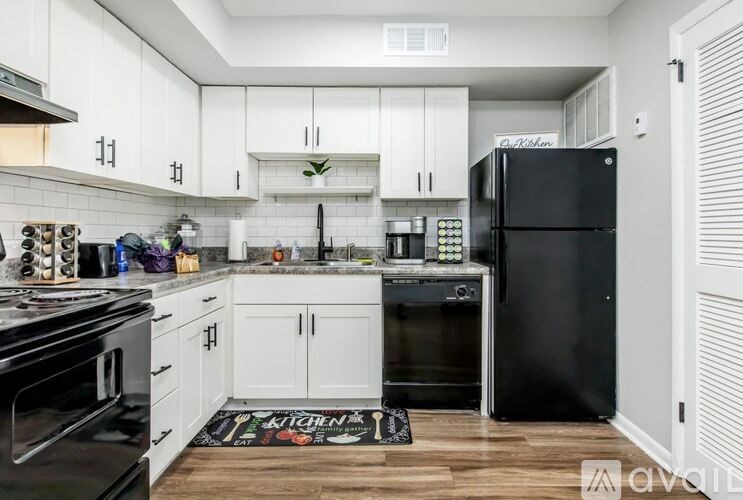 A kitchen with white cabinets and black appliances.