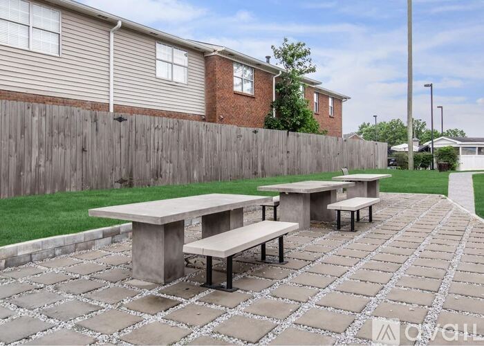 A patio with a table and benches in front of a house.