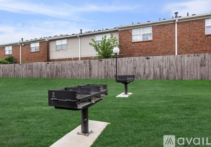 A backyard with a lawn, a grill, and a lamp post.