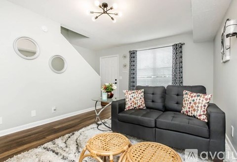 A living room with a black couch and a round mirror on the wall.