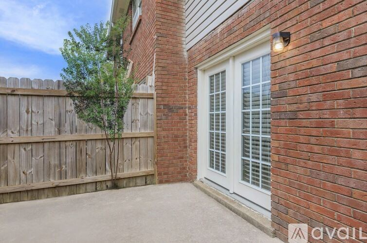 A small tree is planted in a wooden fence.
