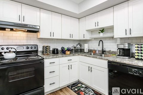 A kitchen with black appliances and white cabinets.