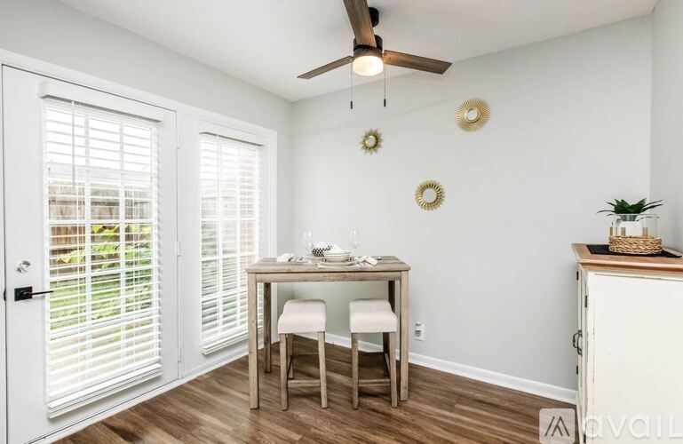 A room with a table and chairs and a ceiling fan.