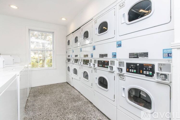 A row of white washing machines in a laundry room.