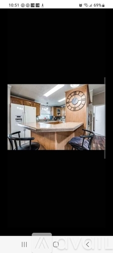 A kitchen with a clock on the wall and a table with chairs.