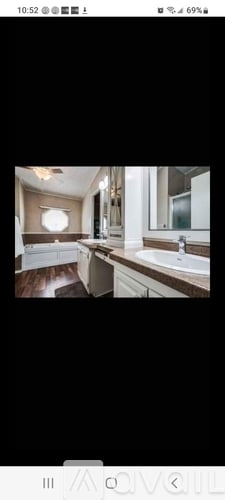 A modern kitchen with white cabinets and a wooden floor.