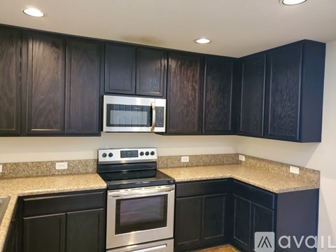 A kitchen with dark wood cabinets and stainless steel appliances.