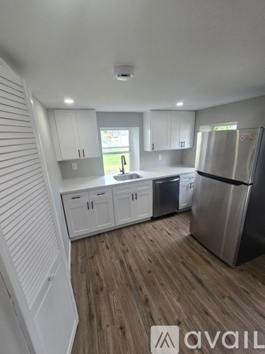 A kitchen with white cabinets and a wooden floor.
