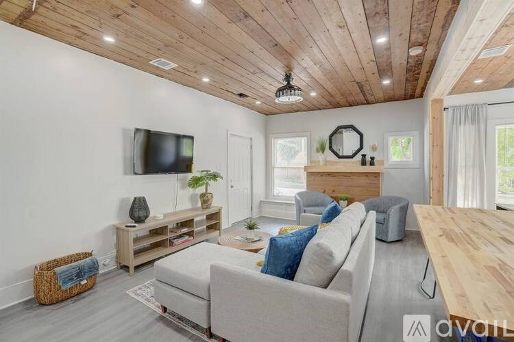 A living room with a grey couch, a wooden table, and a television on the wall.