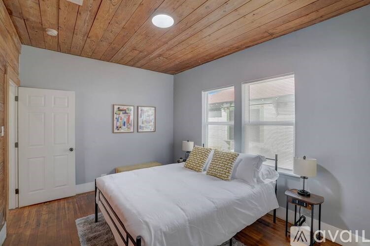 A bedroom with a bed, nightstand, and a window.