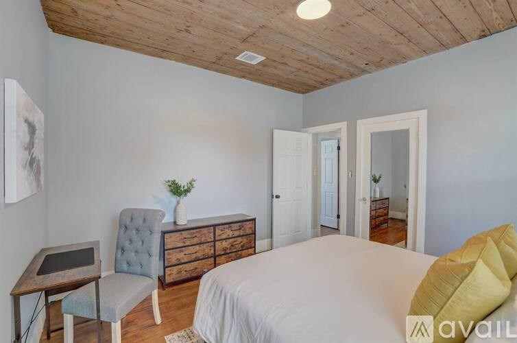 A bedroom with a bed, chair, and cabinet.