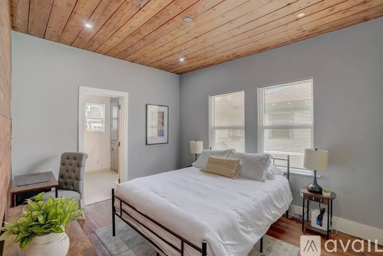 A bedroom with a white bed and a wooden ceiling.