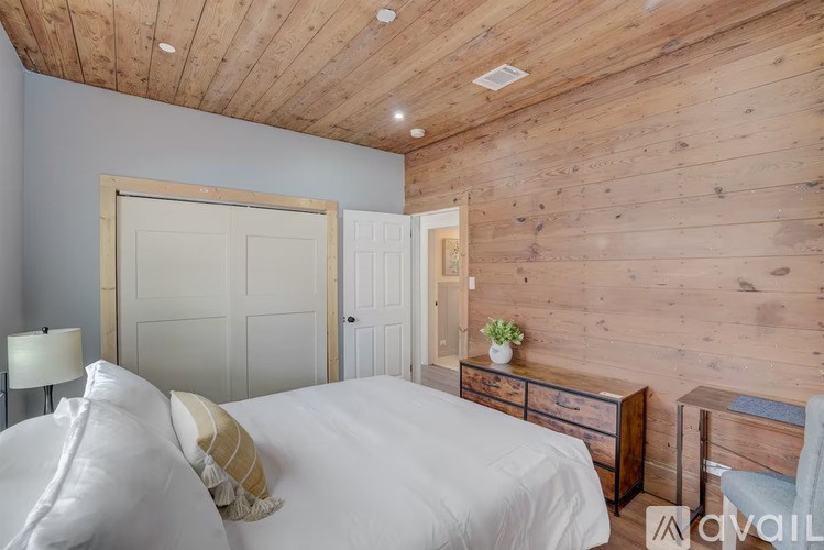 A bedroom with a bed, nightstand, and chair.