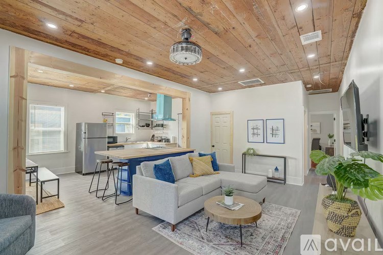 A living room with a grey couch and a wooden ceiling.