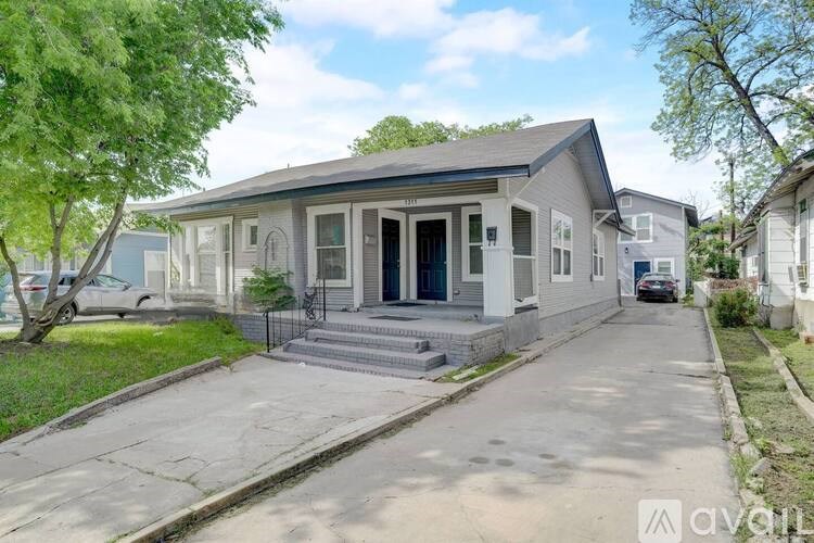 A house with a grey front yard and a black gate.
