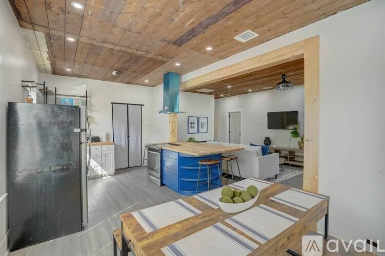 A kitchen with a wooden ceiling and a blue island.