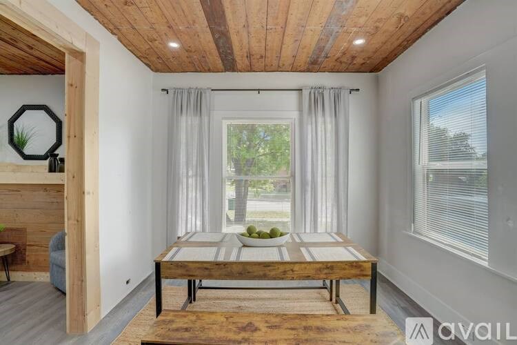 A wooden table is in the middle of a room with a window and a couch.