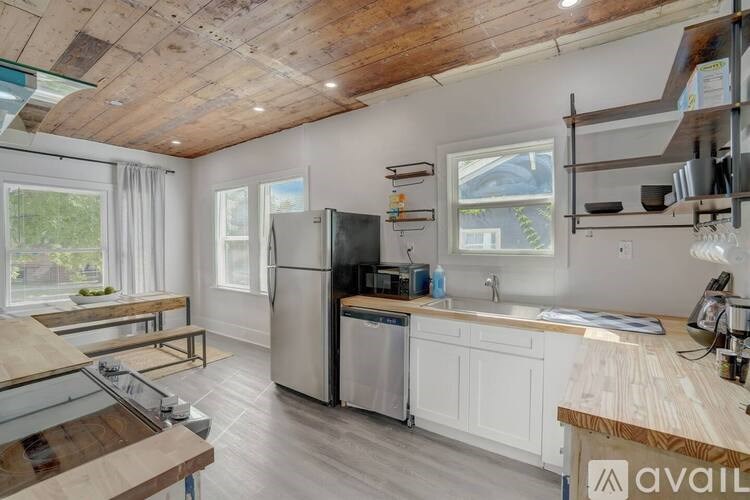 A kitchen with a wooden ceiling and a refrigerator.