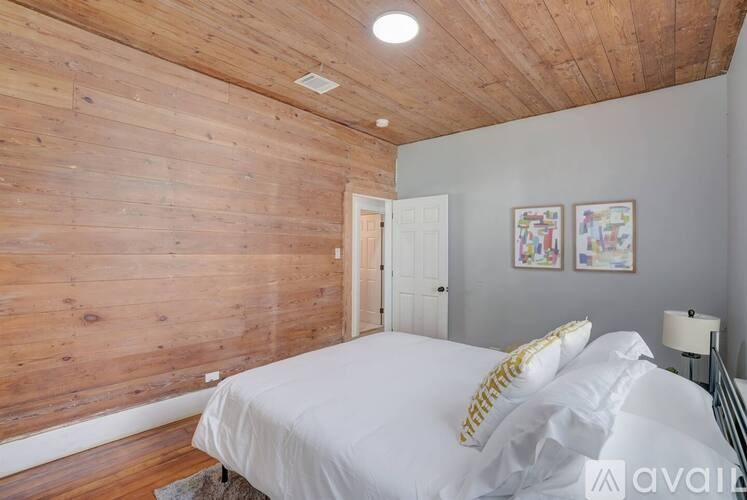 A bedroom with a white bed and wooden walls.