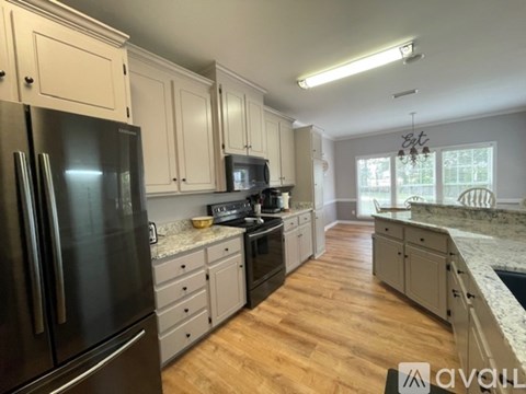 A kitchen with a black refrigerator and wooden floors.