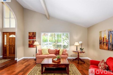 A living room with a red couch and a wooden floor.