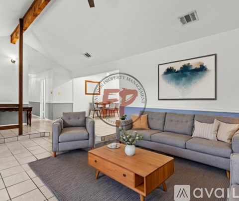 A living room with a grey couch, a wooden coffee table, and a painting on the wall.