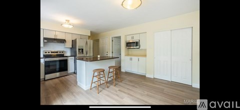 A kitchen with white cabinets and a wooden floor.