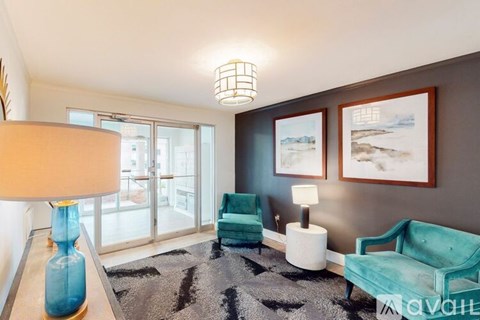 A living room with a blue couch, a lamp, and a painting on the wall.