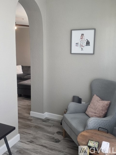 A living room with a grey couch and a framed picture on the wall.