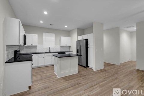 A modern kitchen with white cabinets and a black countertop.