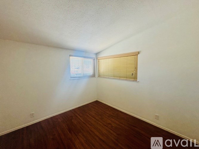 A room with wooden floors and a window with blinds.