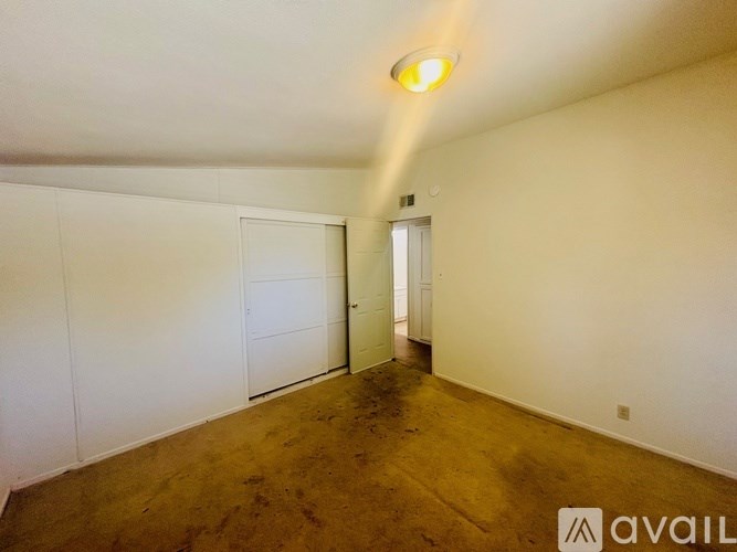 A room with a white door and a white wall with a light on the ceiling.