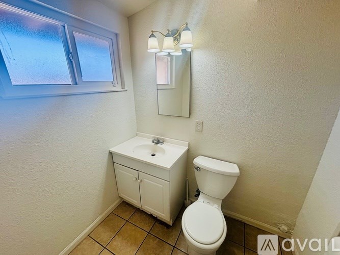 A small bathroom with a toilet, sink, and cabinet.