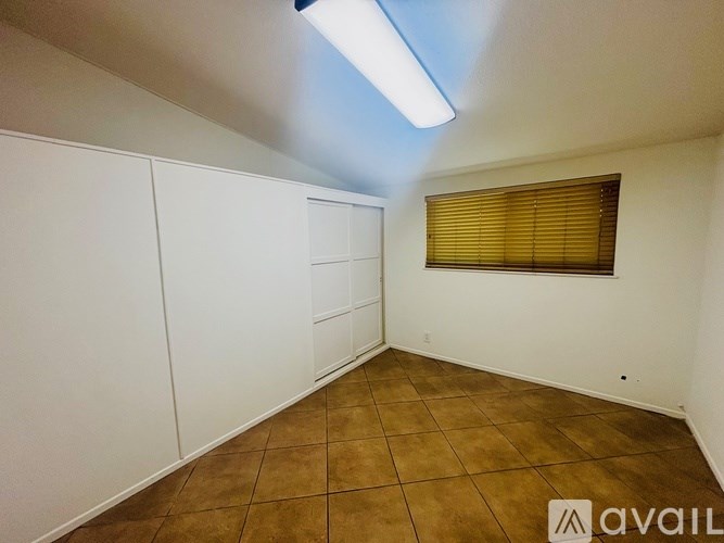 A room with brown tiles and white walls is available for rent.