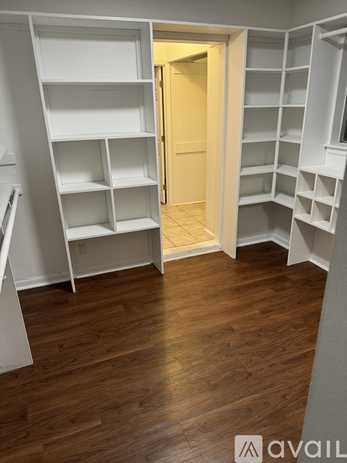A room with white shelves and a wooden floor.