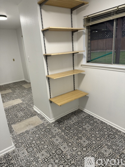 A room with a shelving unit and a window.