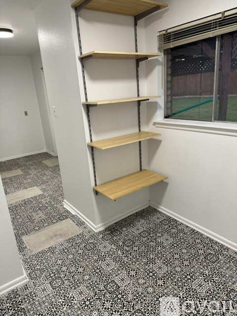 A room with a shelving unit and a window.