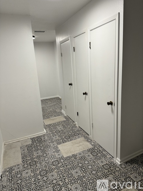 A hallway with white doors and a black and white floor.