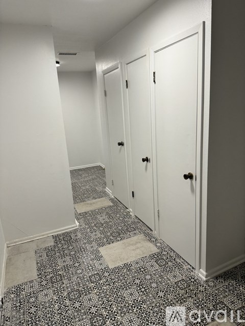 A hallway with white doors and a black and white floor.