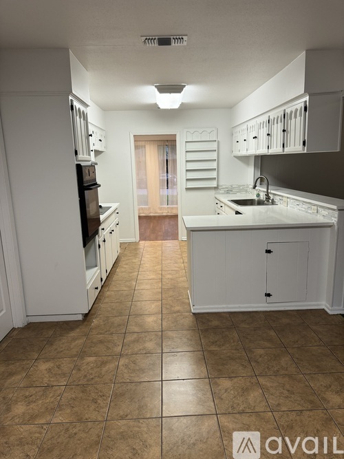 A kitchen with white cabinets and a brown floor.