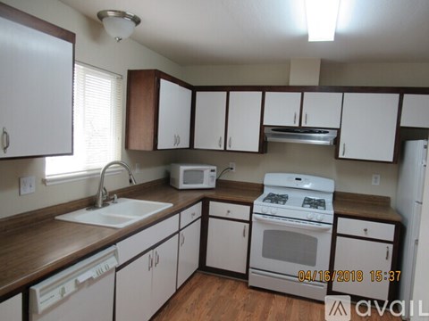 A kitchen with white cabinets and a white stove top oven.