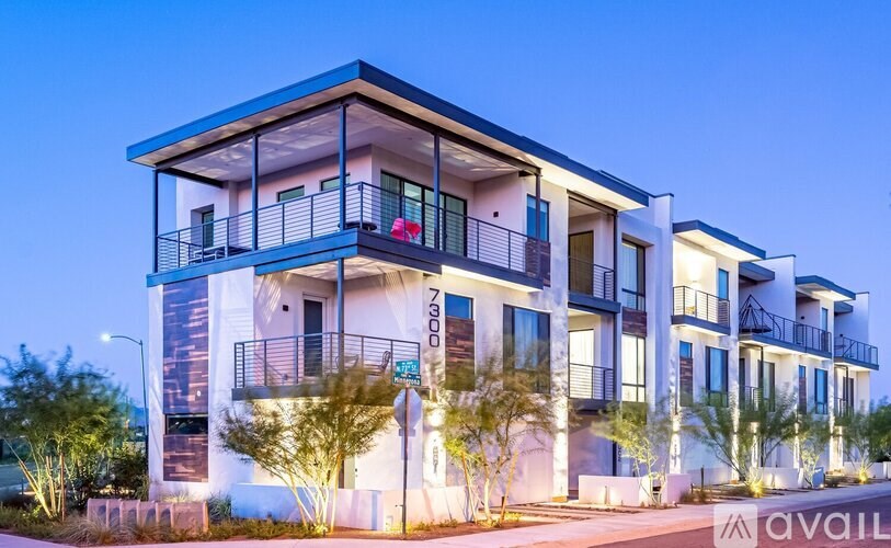A modern multi-story building with balconies and lights on.