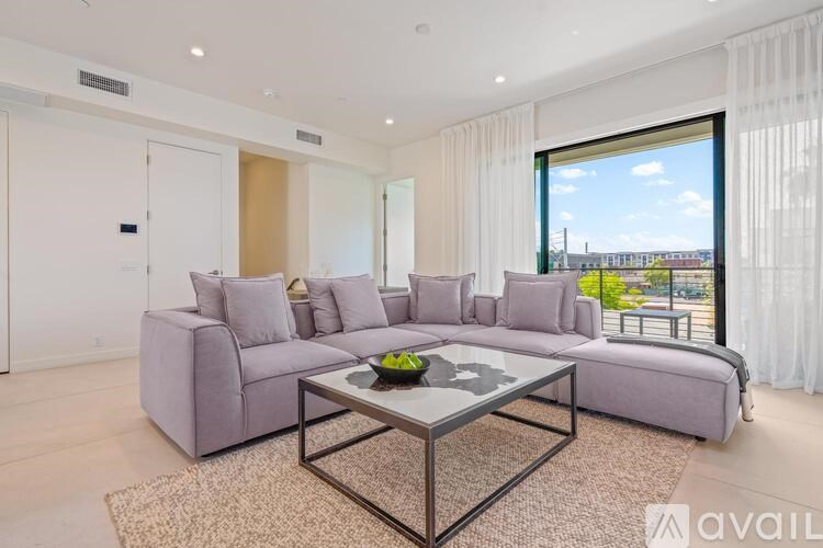 A modern living room with a grey sofa set and a glass coffee table.