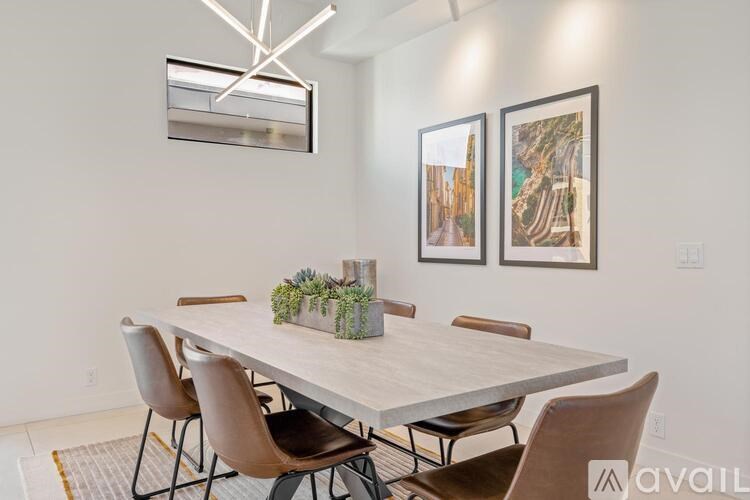 A dining room with a table, chairs, and pictures on the wall.