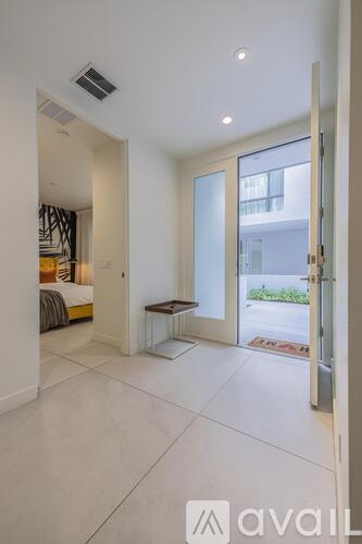 A modern bedroom with a large bed and a glass door leading to a balcony.