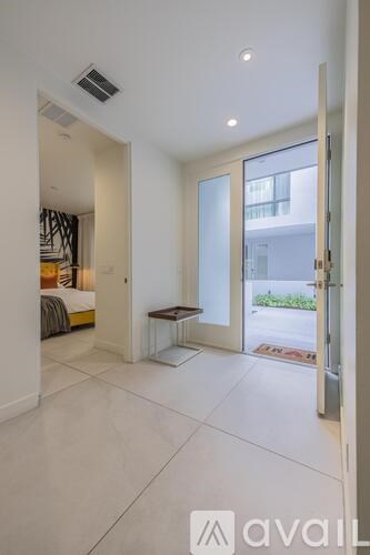 A modern bedroom with a large bed and a glass door leading to a balcony.