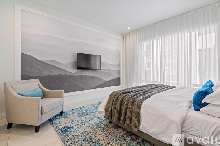 A bedroom with a large bed and a painting on the wall.