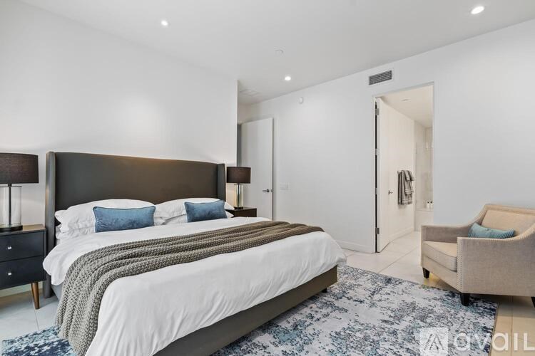 A bedroom with a large bed and a chair.