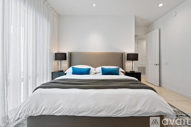 A bedroom with a large bed and two lamps.